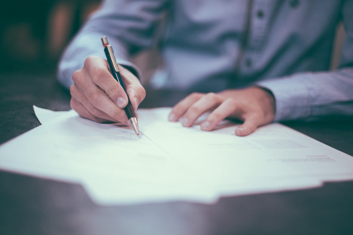 Hands signing legal documents at a desk